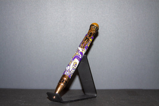 Decorative pen with purple and gold design on a black stand against a gray background