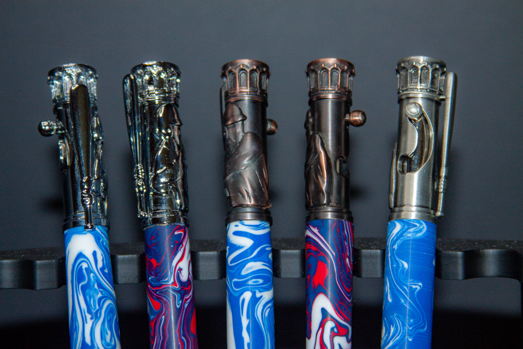 Five Baseball pens with marbled blue and red handles and metallic accents on a dark background